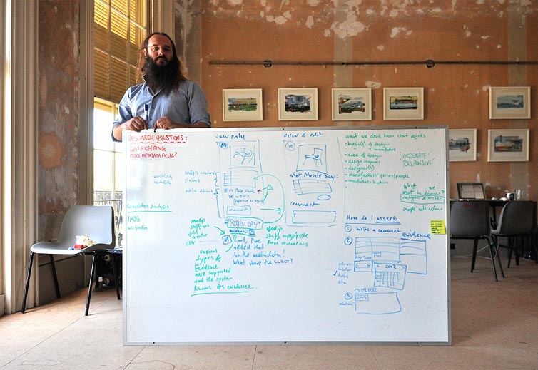 Danny Hoipe standing by a whiteboard in an unrestored drawing room.